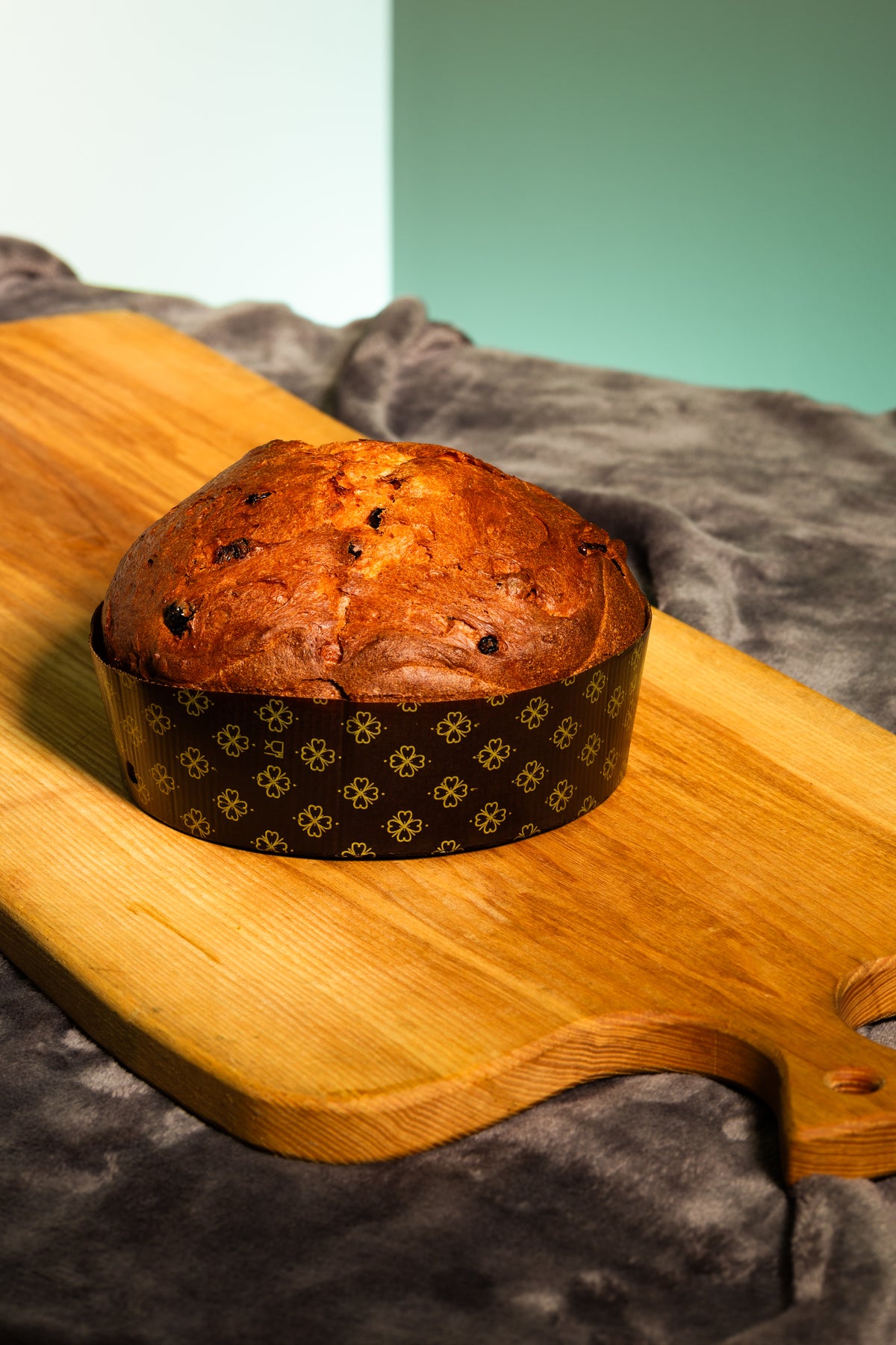 Целый Panettone Rosa al Basin в бумажной форме на деревянной доске.