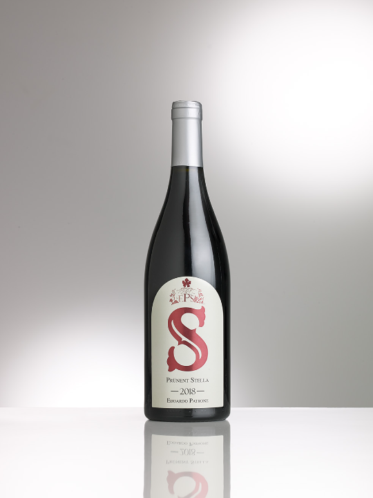 Botella de Prünent Stella Edoardo Patrone sobre una superficie reflectante.