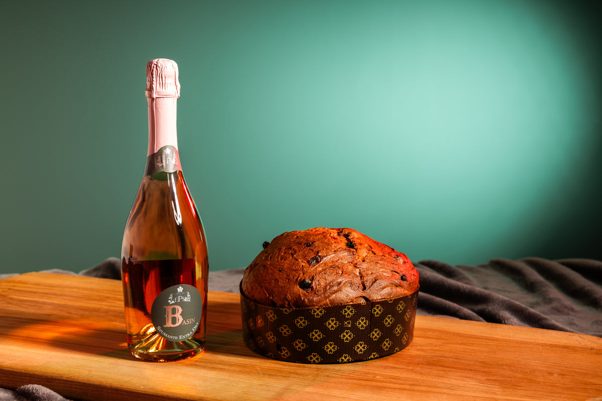 Panettone Rosa и бутылка игристого Basin рядом на деревянной доске.